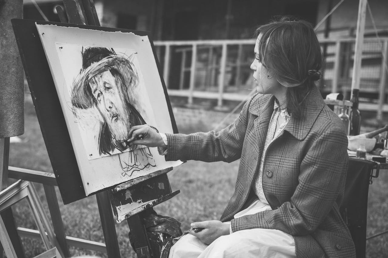 Home Woman painting a portrait outdoors in black and white.